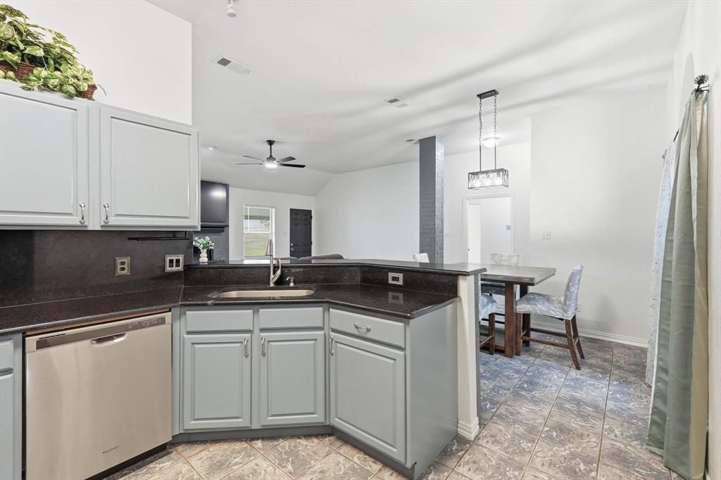 217 Seay Road Italy, TX 76651 - Photo 15 of 38 Kitchen featuring a peninsula, dishwasher, lofted ceiling, dark stone countertops, and ceiling fan