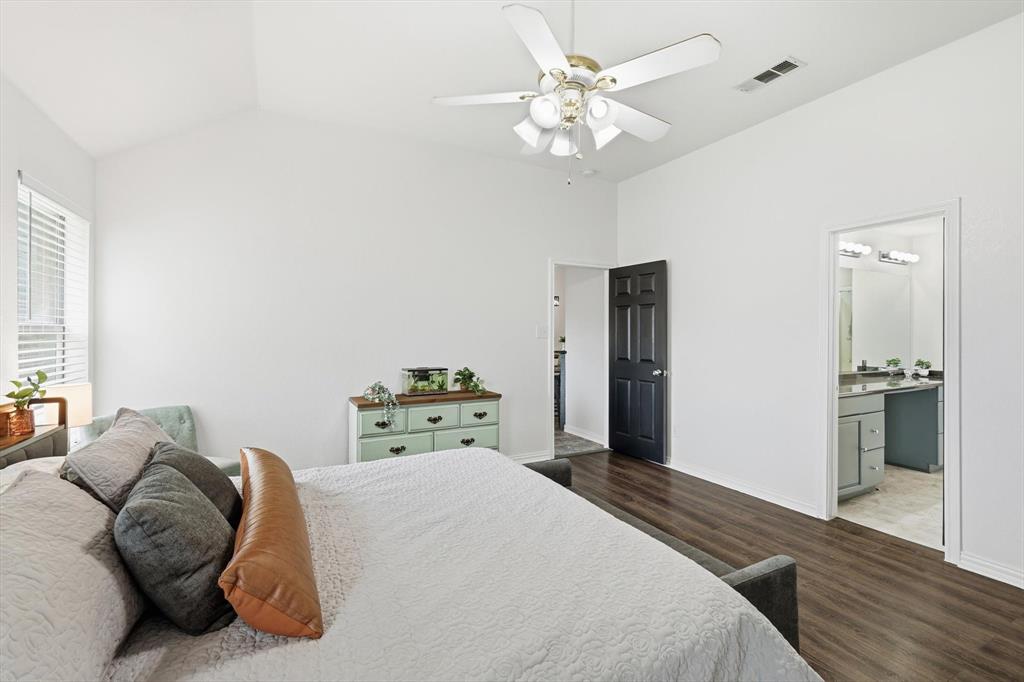 217 Seay Road Italy, TX 76651 - Photo 19 of 38 Bedroom featuring vaulted ceiling, dark wood finished floors, ceiling fan, and ensuite bathroom