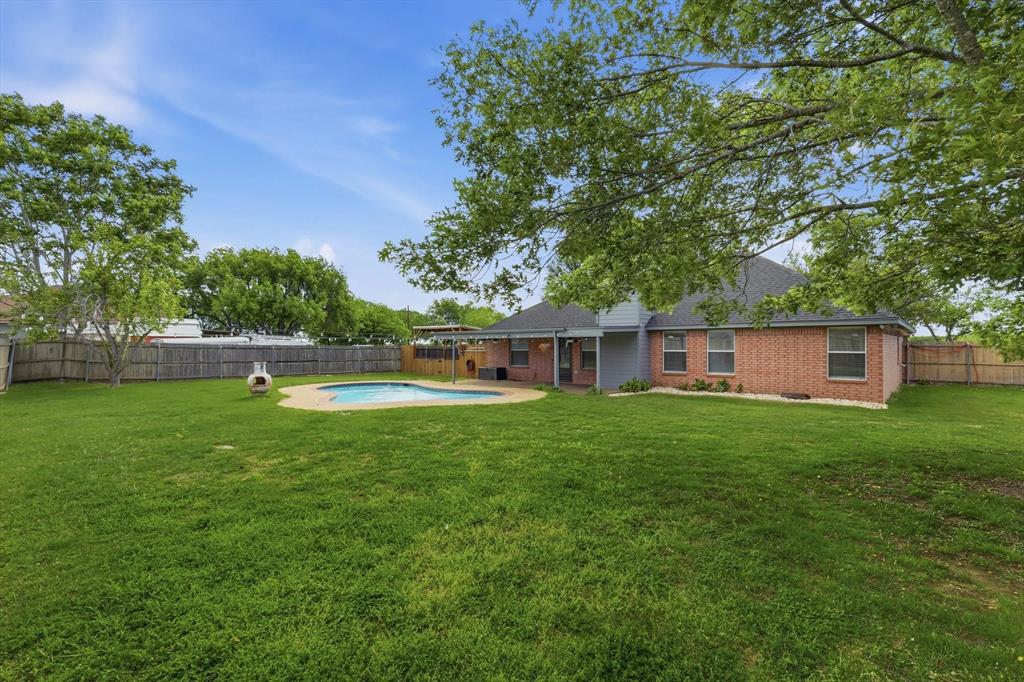 217 Seay Road Italy, TX 76651 - Photo 31 of 38 Rear view of property featuring brick siding, a fenced backyard, a patio area, and a shingled roof