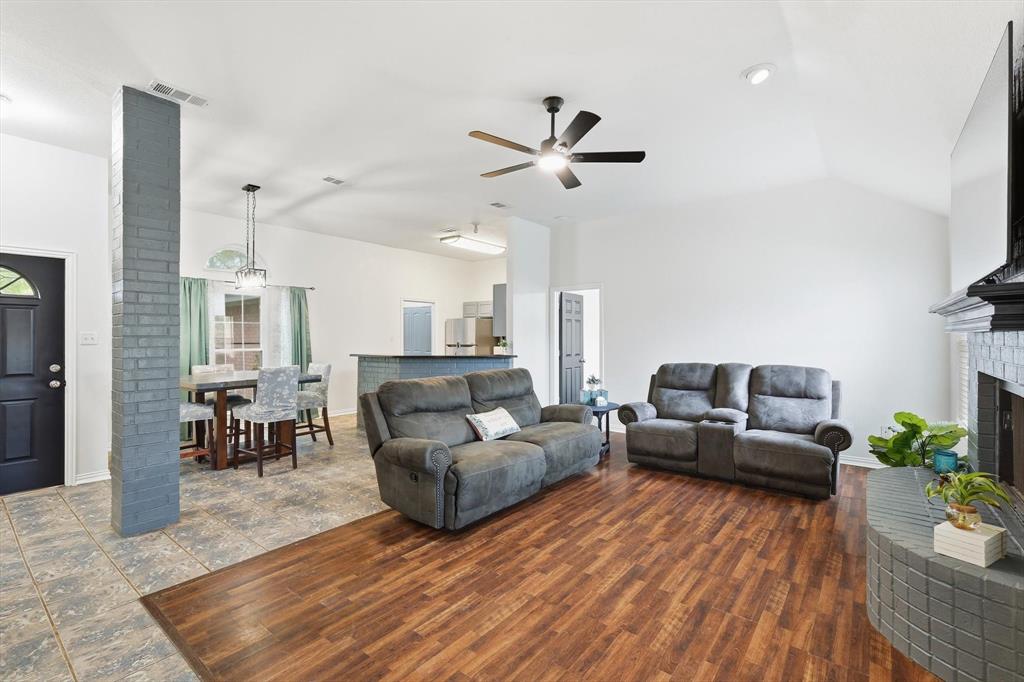 217 Seay Road Italy, TX 76651 - Photo 6 of 38 Living area featuring a brick fireplace, a ceiling fan, vaulted ceiling, and dark wood-type flooring