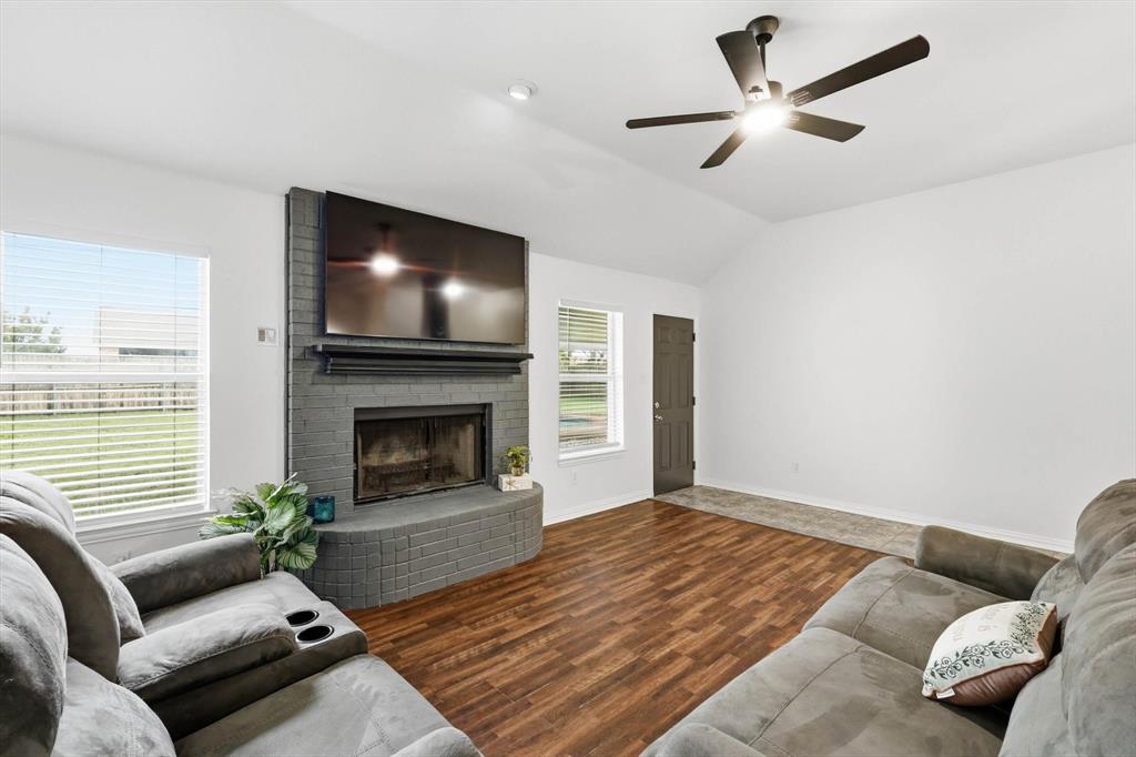 217 Seay Road Italy, TX 76651 - Photo 7 of 38 Living room featuring dark wood finished floors, vaulted ceiling, a brick fireplace, and a ceiling fan