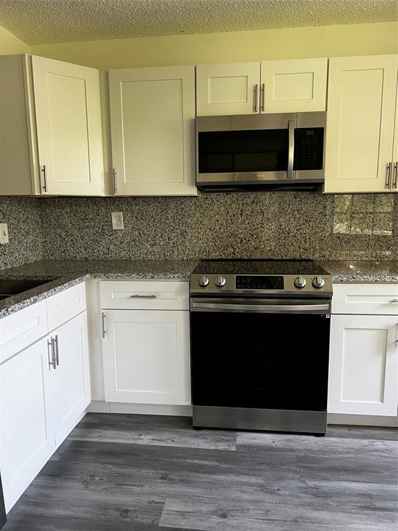 6596 Via Regina, Unit 6596 Boca Raton, FL 33433 - Photo 4 of 16 a kitchen with granite countertop a stove and a microwave