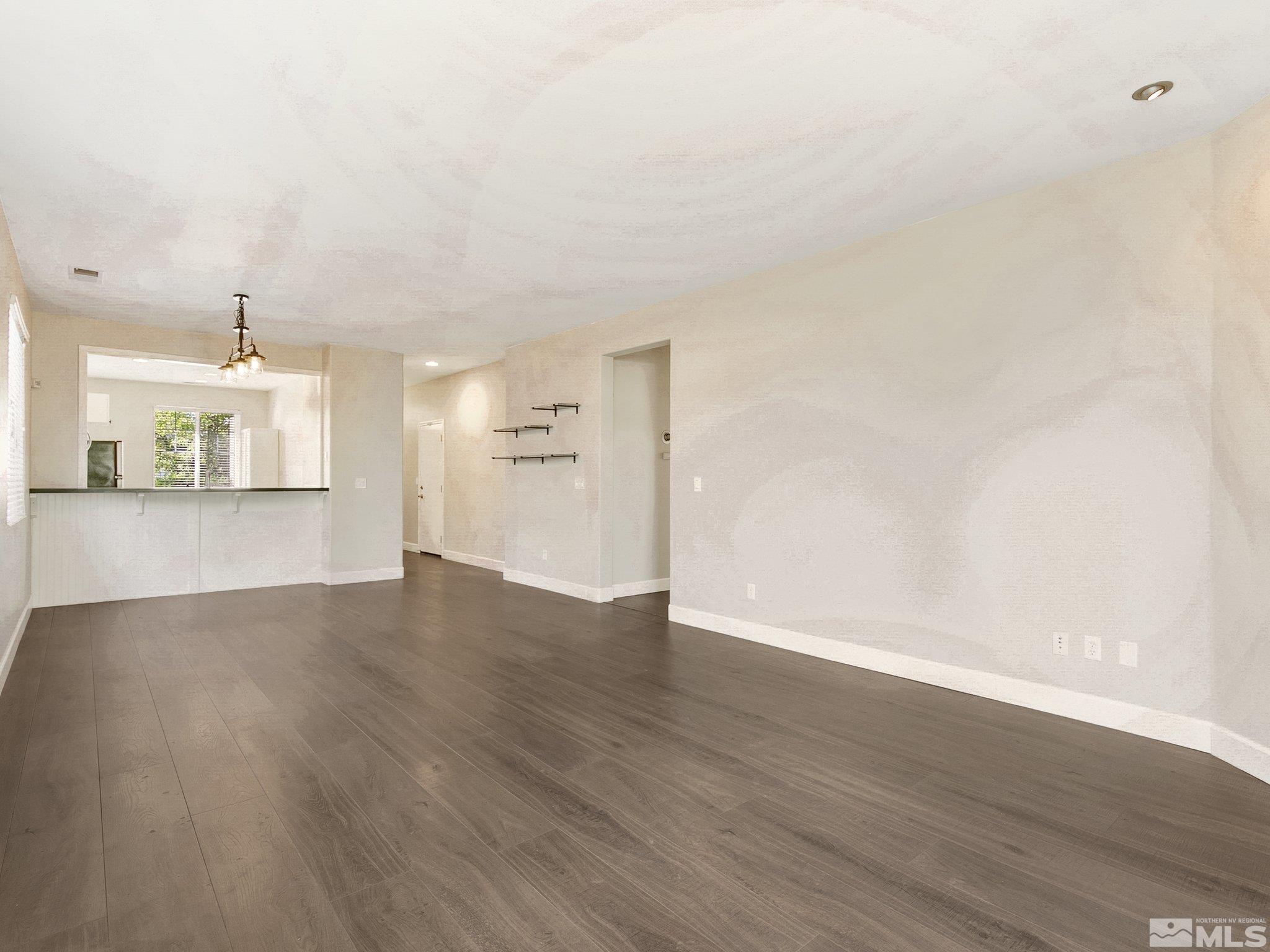 2348 Clementine Lane Reno, NV 89521 - Photo 17 of 38 an empty room with wooden floor and kitchen view