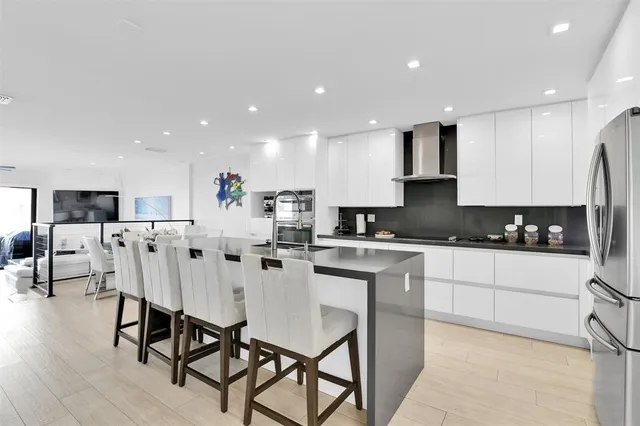 a large white kitchen with stainless steel appliances kitchen island granite countertop a refrigerator and a stove top oven