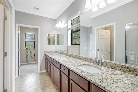 a bathroom with a granite countertop double vanity sink and a mirror