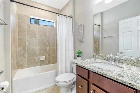 a bedroom with a bed television on desk and a window
