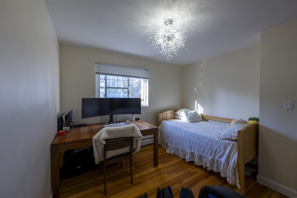 18 Emerson Gardens Road, Unit 18 Lexington, MA 02420 - Photo 13 of 23 a bedroom with a bed and a chandelier