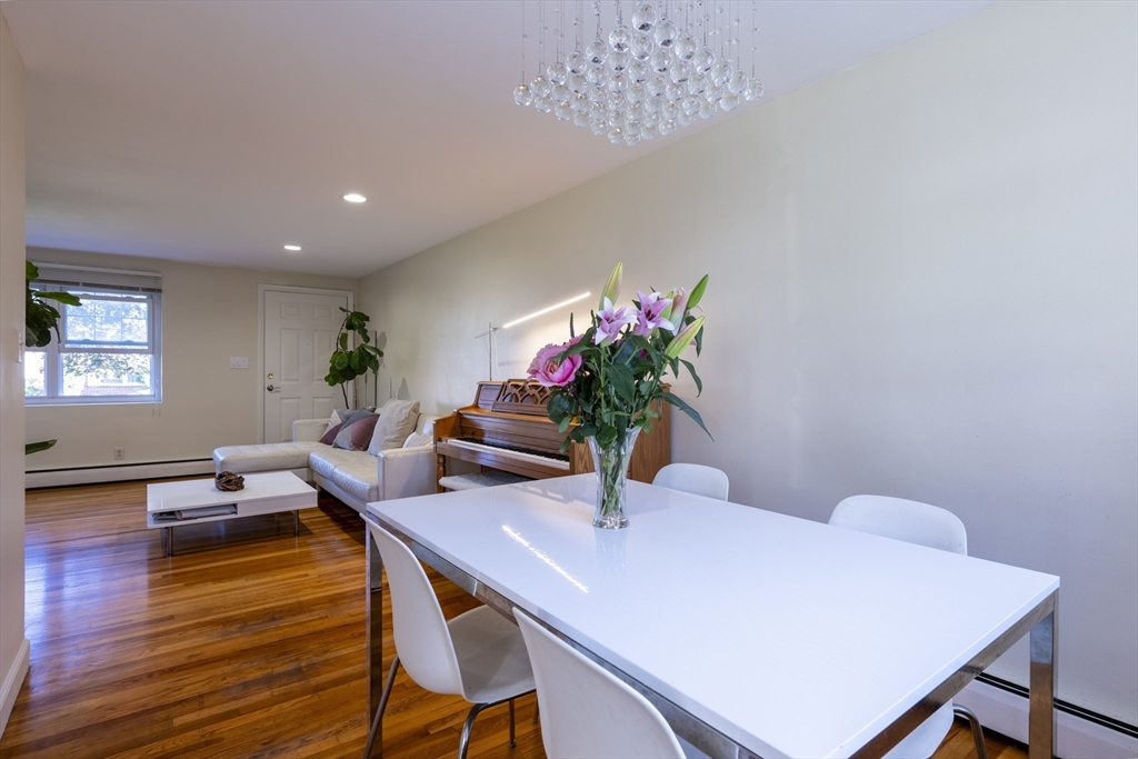 18 Emerson Gardens Road, Unit 18 Lexington, MA 02420 - Photo 4 of 23 a dining room with furniture potted plants and wooden floor