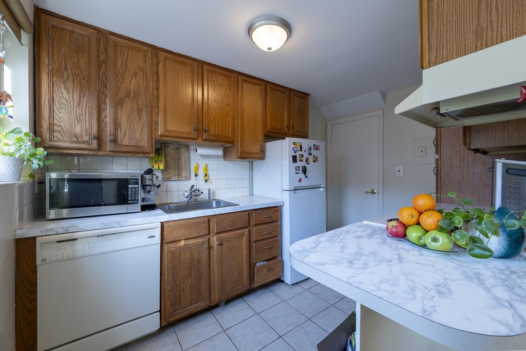 18 Emerson Gardens Road, Unit 18 Lexington, MA 02420 - Photo 5 of 23 a kitchen with stainless steel appliances kitchen island granite countertop wooden cabinets