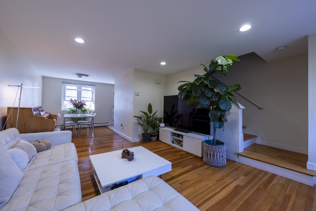 18 Emerson Gardens Road, Unit 18 Lexington, MA 02420 - Photo 7 of 23 a living room with furniture potted plant and a flat screen tv