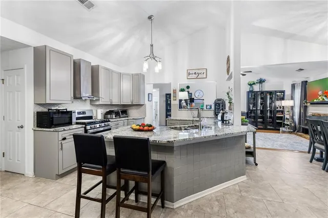 a kitchen with kitchen island a dining table chairs cabinets and stainless steel appliances