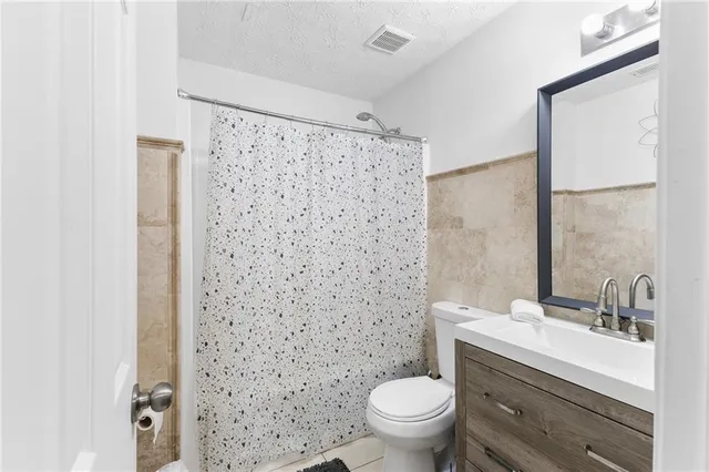 a bathroom with a sink a toilet and shower curtain