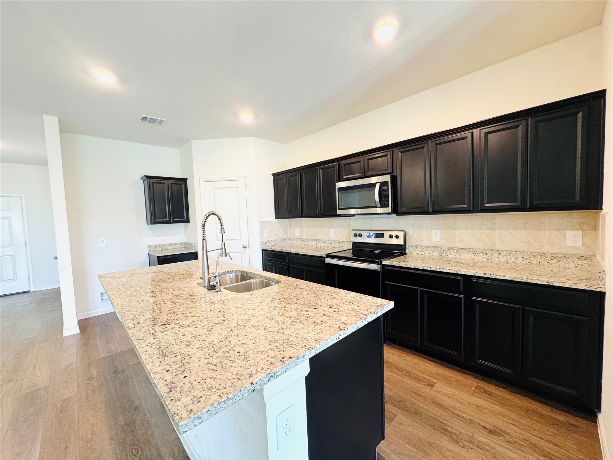1013 Pitch Pine Brookshire, TX 77423 - Photo 7 of 30 a kitchen with stainless steel appliances kitchen island granite countertop a sink dishwasher stove and microwave with wooden floor