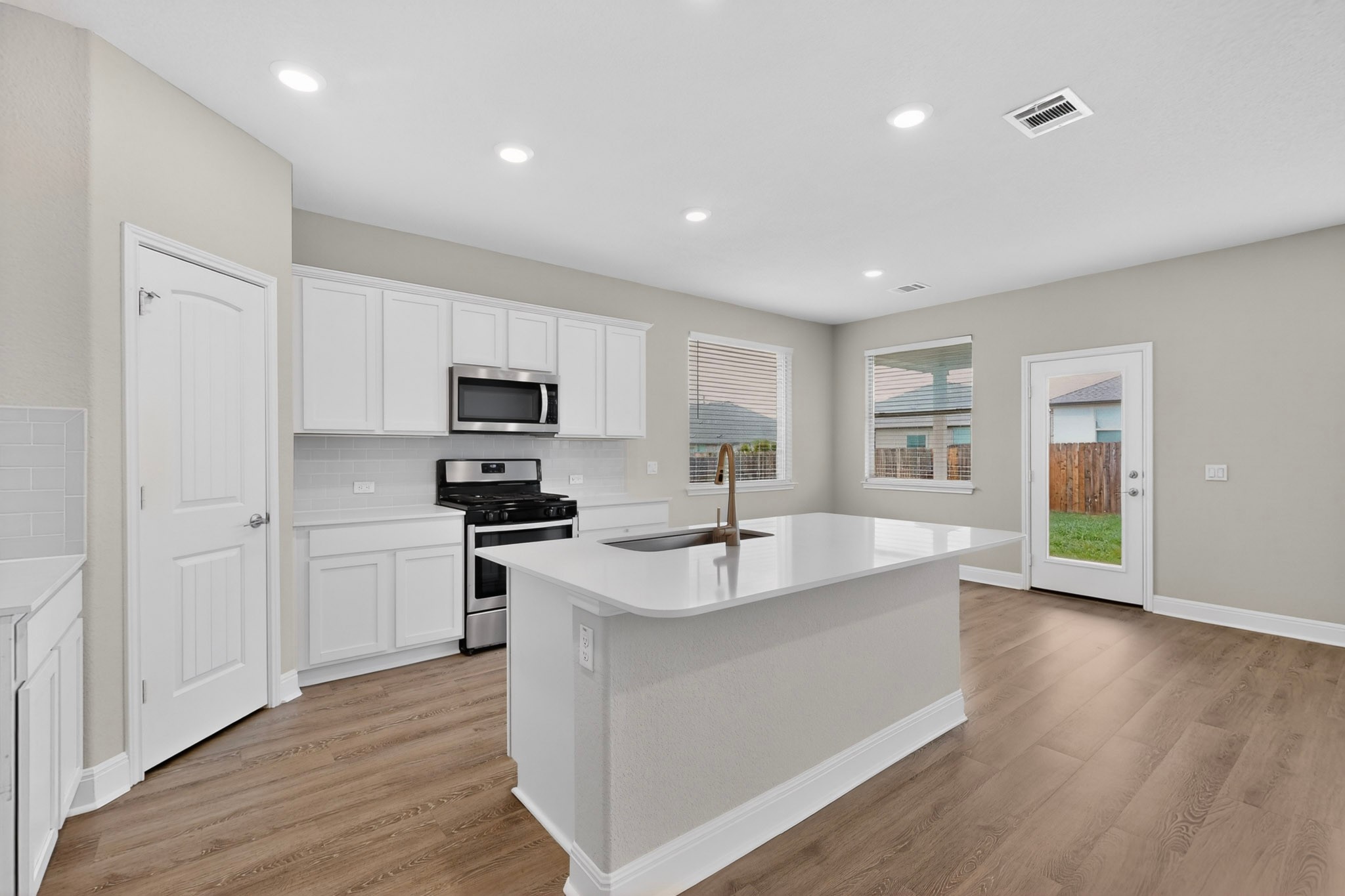 16809 Guido Cove Pflugerville, TX 78660 - Photo 10 of 40 Kitchen featuring white cabinetry, stainless steel appliances, a center island with sink, wood-finish flooring, and recessed lighting