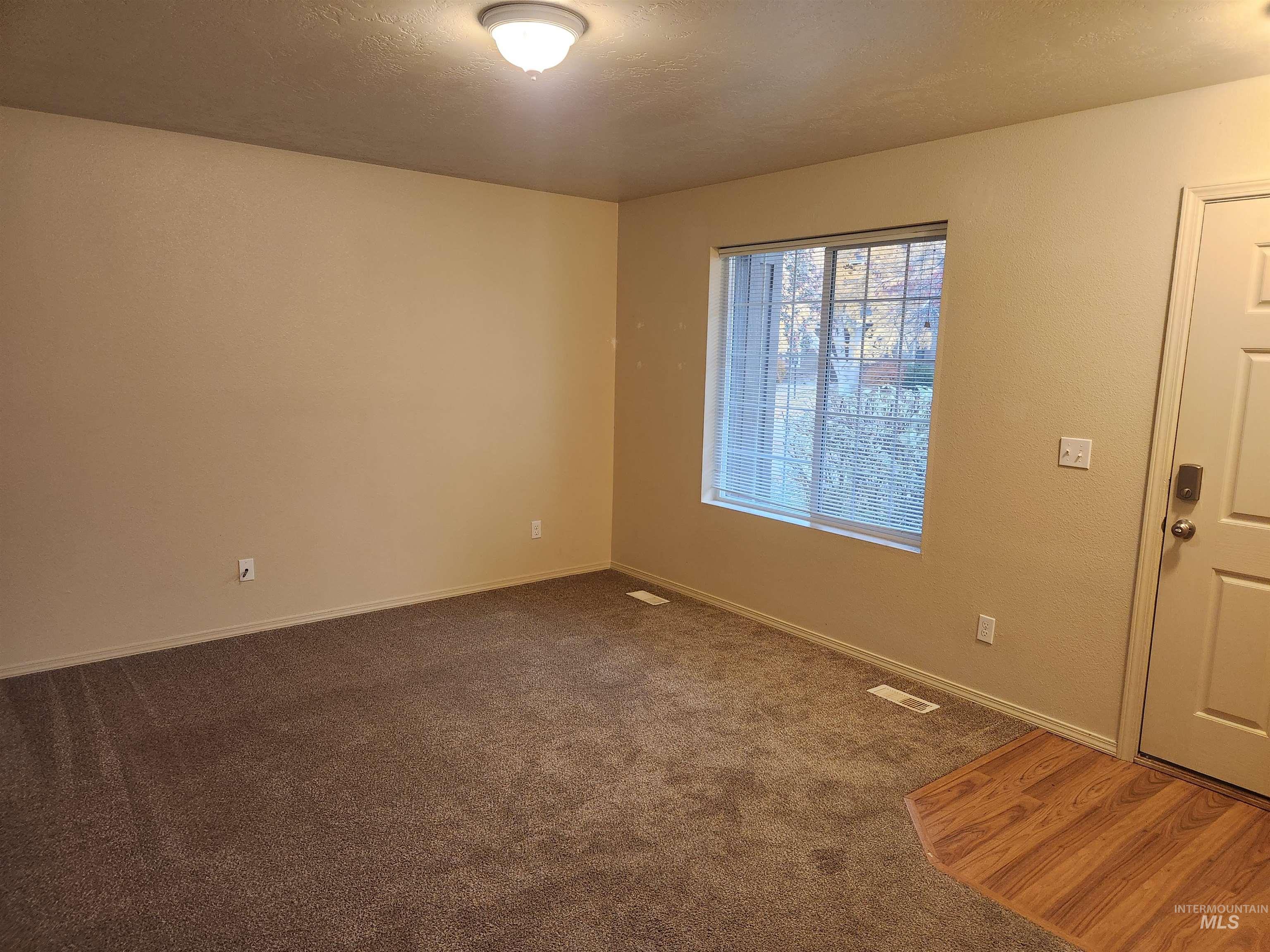 9962 West Rustica Street Boise, ID 83709 - Photo 2 of 15 Spare room featuring dark colored carpet and a textured ceiling