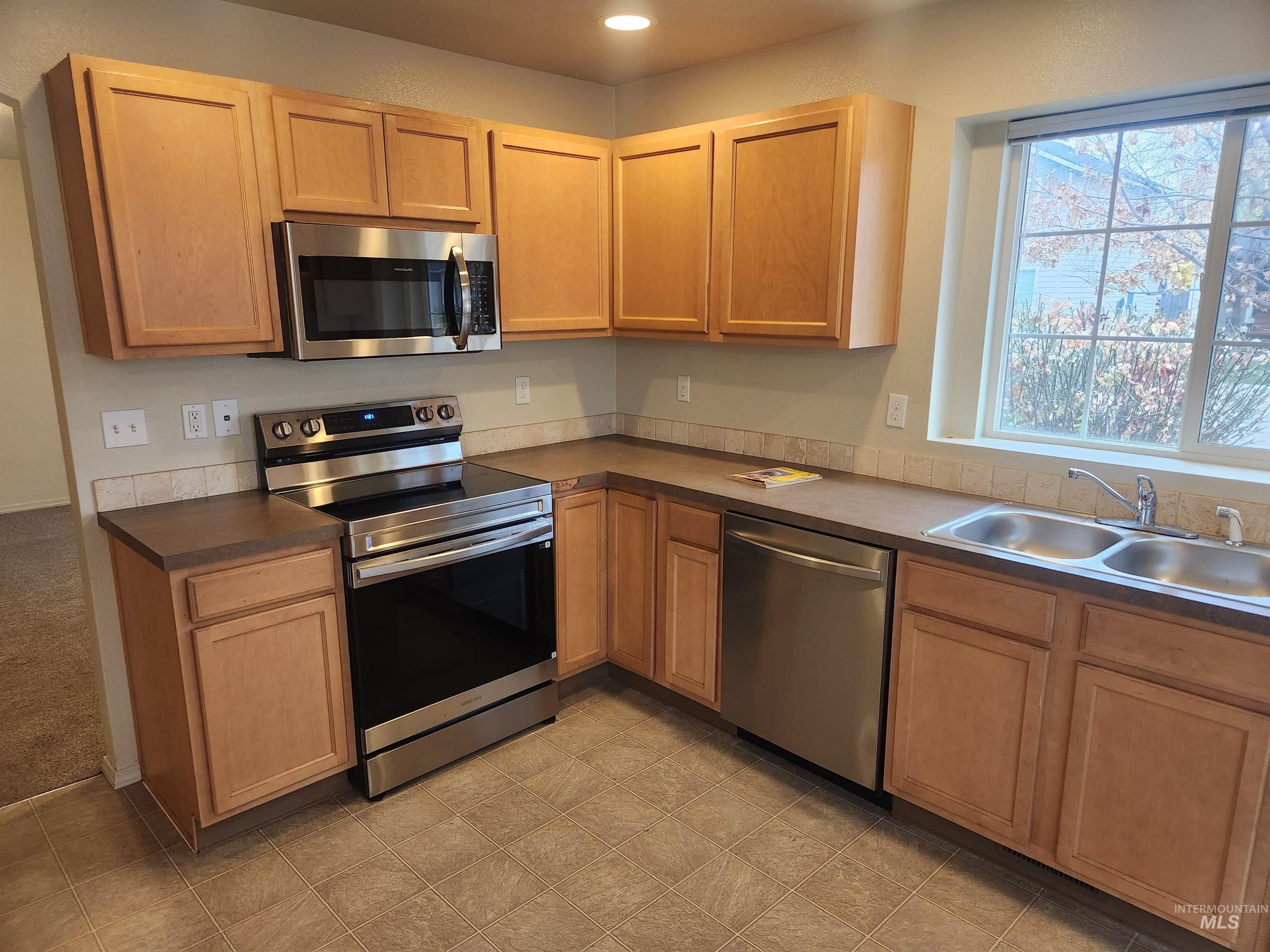 9962 West Rustica Street Boise, ID 83709 - Photo 3 of 15 Kitchen featuring dark countertops, white appliances, recessed lighting, light flooring, and brown cabinets
