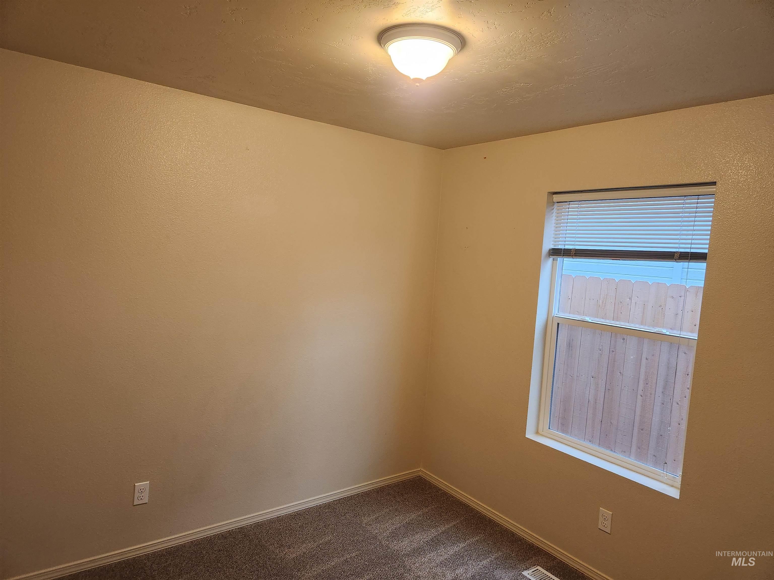 9962 West Rustica Street Boise, ID 83709 - Photo 9 of 15 Empty room with dark colored carpet and baseboards