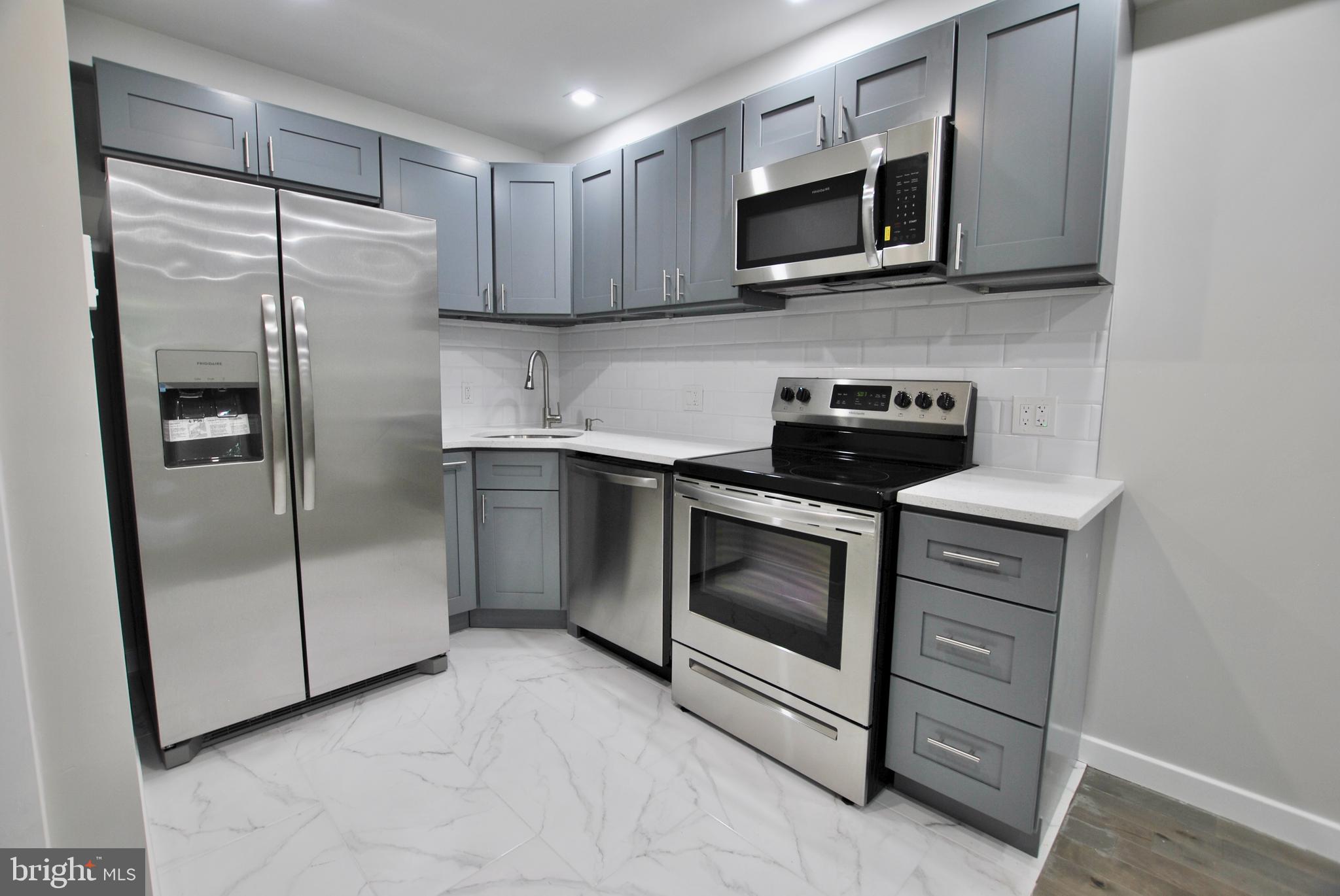 2153 North 19th Street, Unit 4 Philadelphia, PA 19121 - Photo 2 of 17 a kitchen with stainless steel appliances granite countertop a refrigerator and a stove top oven