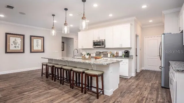a kitchen with kitchen island granite countertop a sink a center island and stainless steel appliances