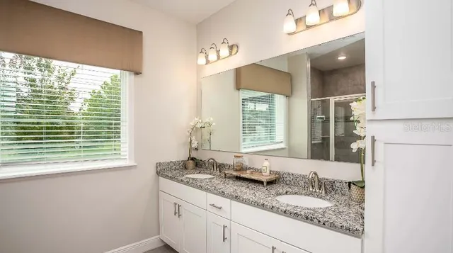 a bathroom with a granite countertop sink and a large mirror next to a window