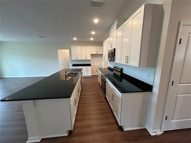 a kitchen with stainless steel appliances kitchen island granite countertop a stove a sink and a refrigerator