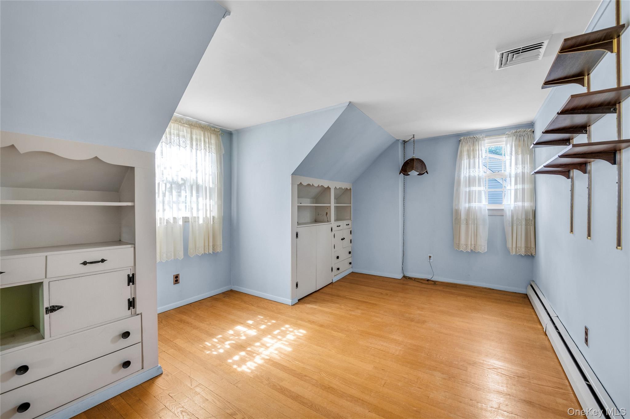 21 Farragut Road Old Bethpage, NY 11804 - Photo 14 of 22 Additional living space featuring baseboard heating, light wood-style flooring, built in features, and vaulted ceiling