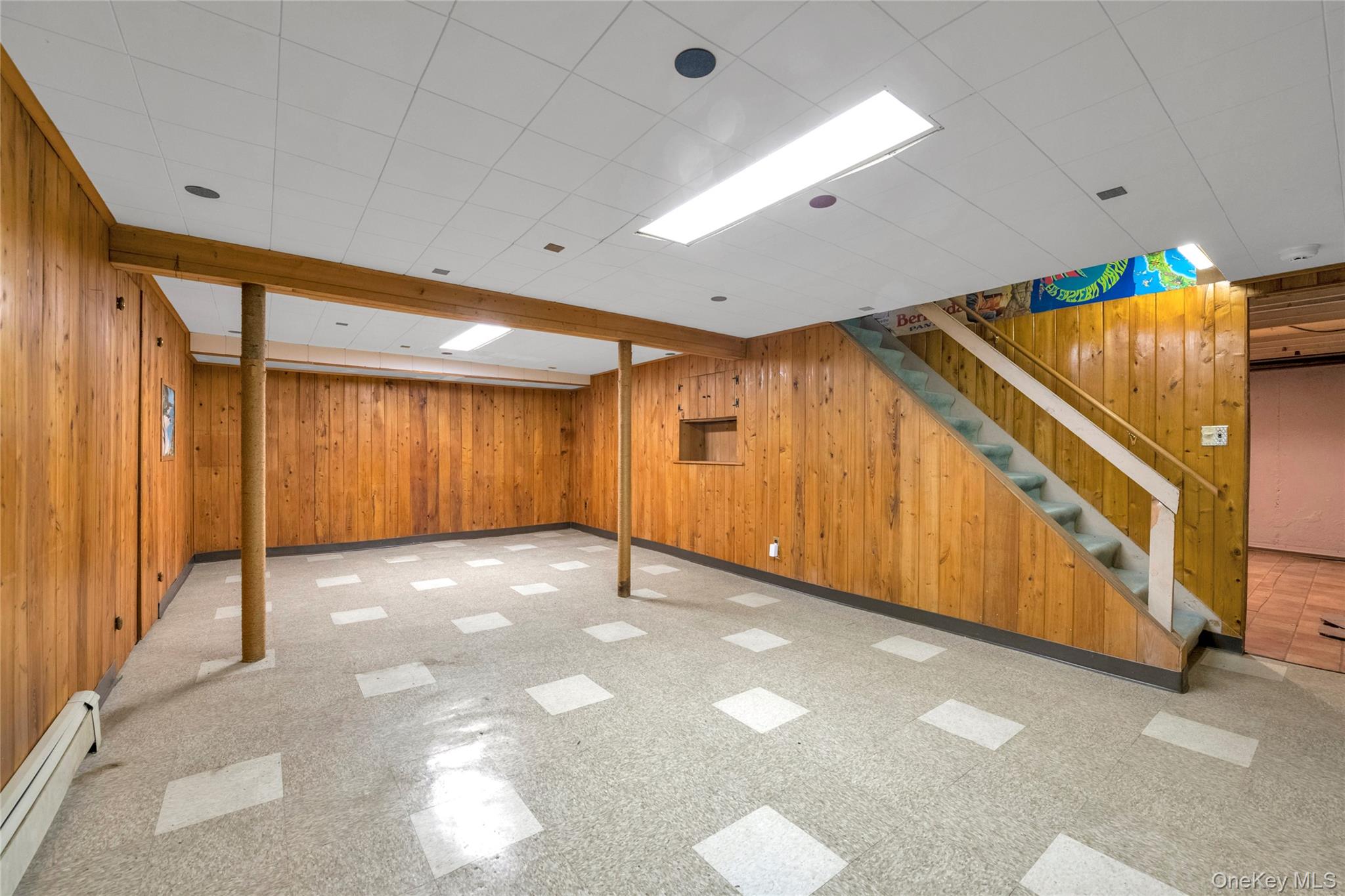 21 Farragut Road Old Bethpage, NY 11804 - Photo 18 of 22 Finished below grade area featuring wood walls, a baseboard radiator, stairs, and light floors