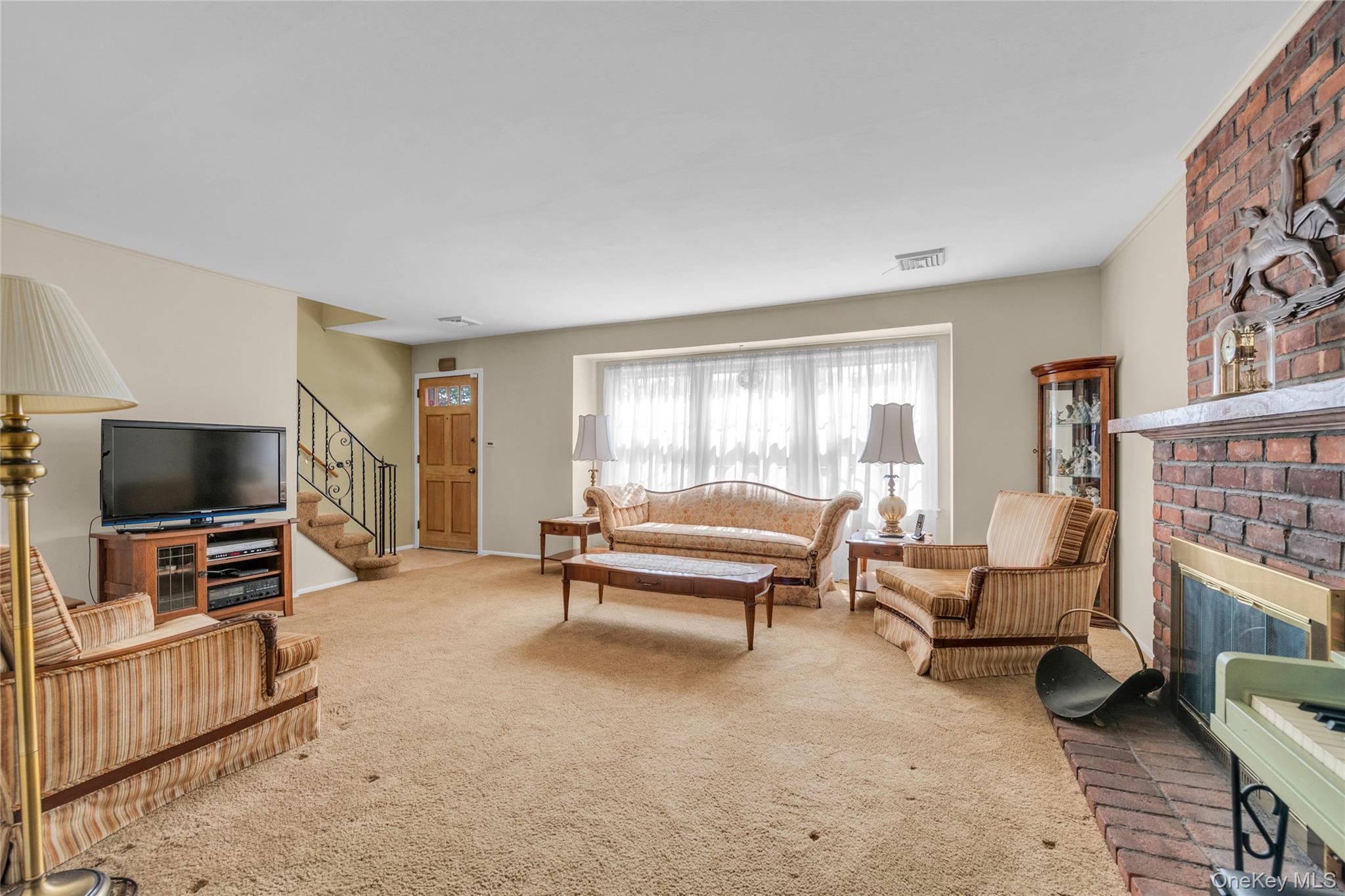 21 Farragut Road Old Bethpage, NY 11804 - Photo 2 of 22 Living room with a brick fireplace, carpet flooring, and stairs