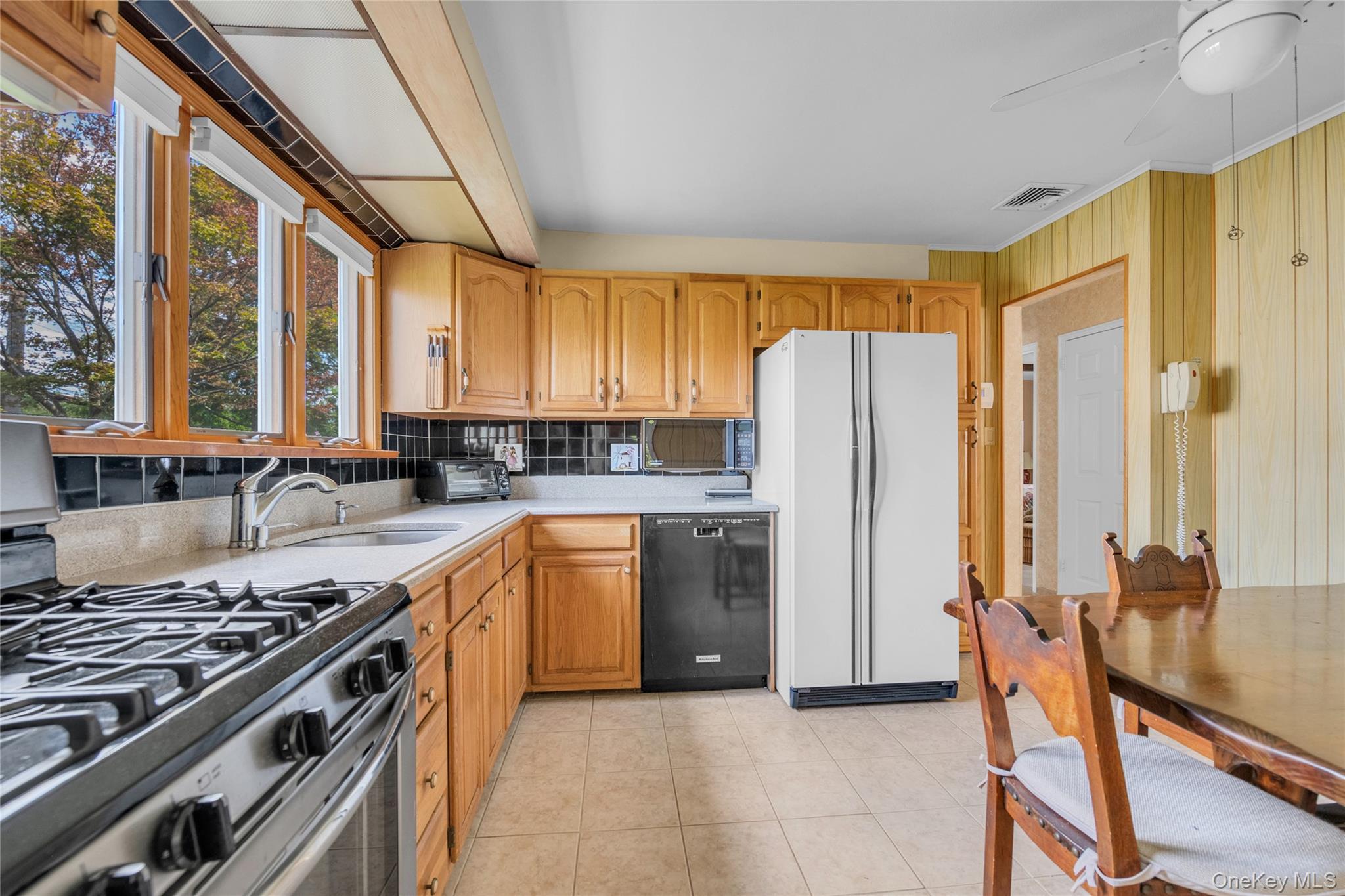 21 Farragut Road Old Bethpage, NY 11804 - Photo 7 of 22 Kitchen featuring stainless steel gas range, black dishwasher, freestanding refrigerator, tasteful backsplash, and light tile patterned flooring