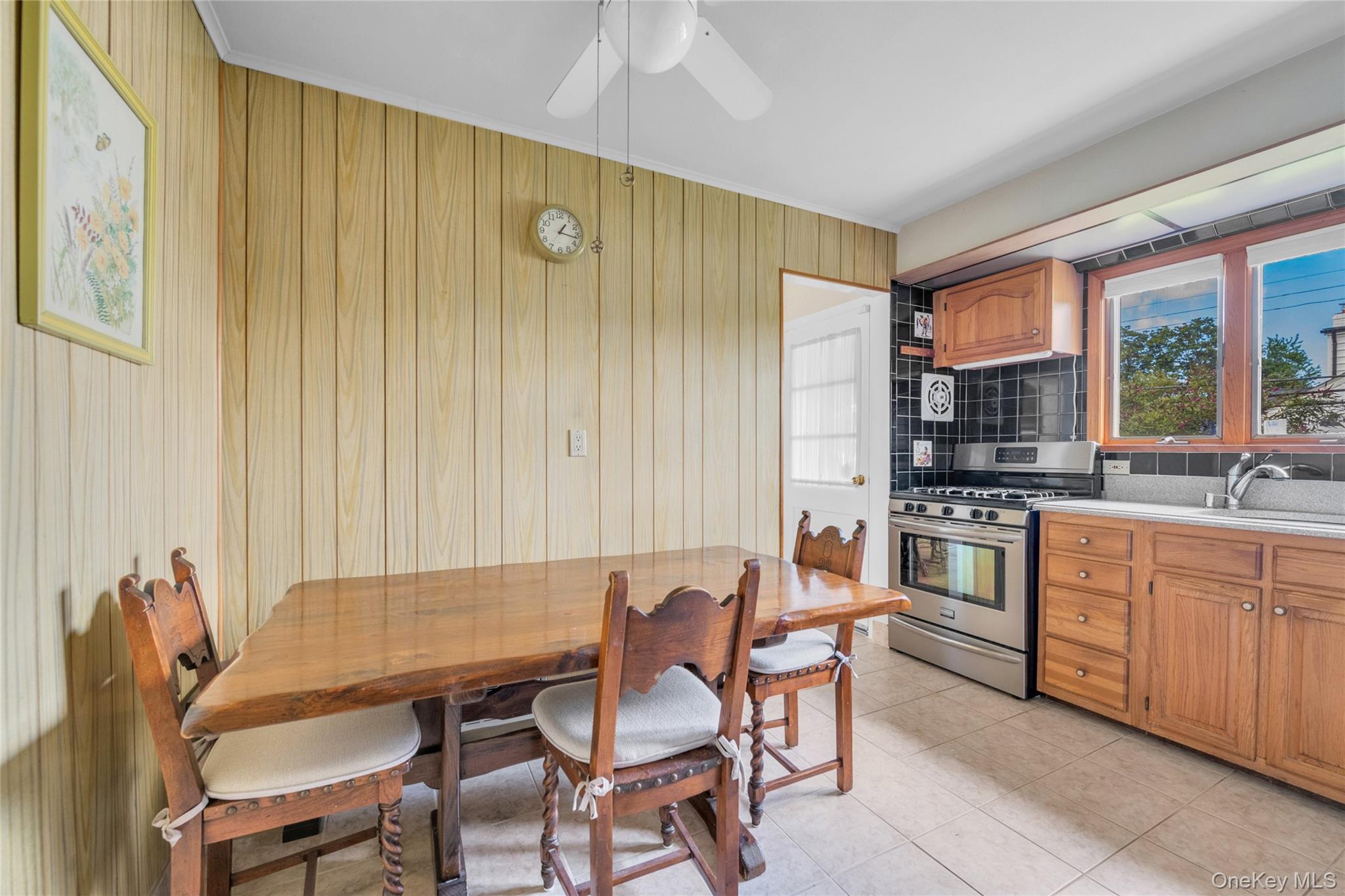 21 Farragut Road Old Bethpage, NY 11804 - Photo 8 of 22 Kitchen featuring stainless steel range with gas stovetop, brown cabinetry, tasteful backsplash, light tile patterned floors, and a ceiling fan