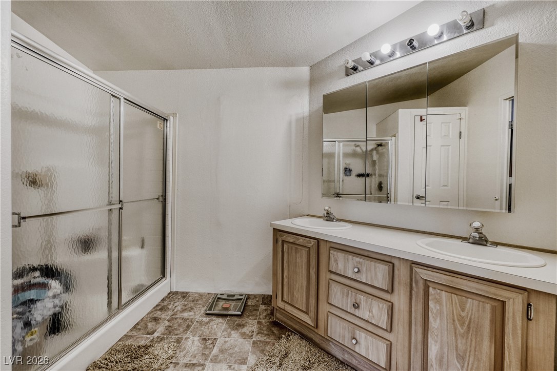 4552 Royal Ridge Avenue Las Vegas, NV 89103 - Photo 11 of 13 Full bath featuring double vanity, a shower stall, and a textured ceiling
