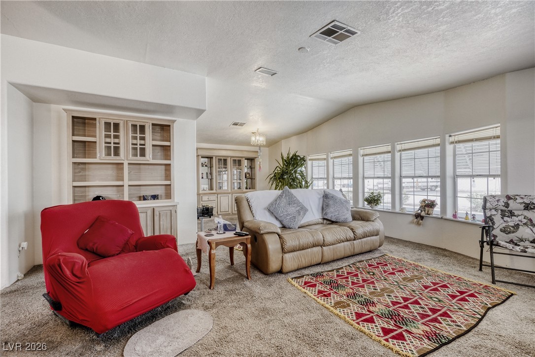 4552 Royal Ridge Avenue Las Vegas, NV 89103 - Photo 3 of 13 Living area featuring carpet, vaulted ceiling, and a textured ceiling