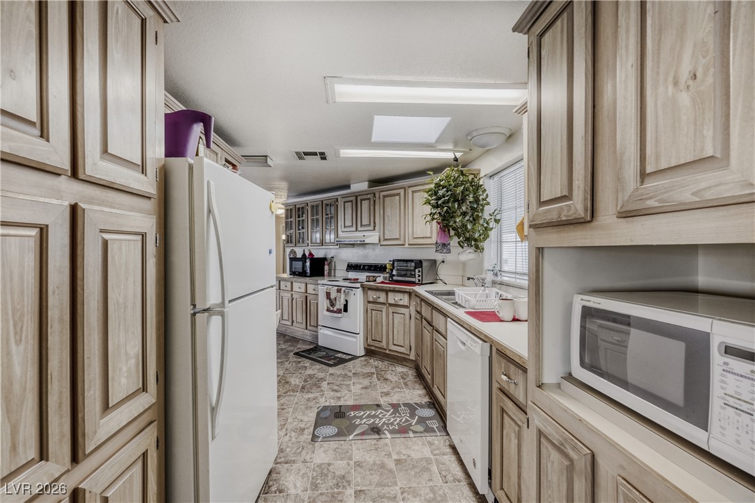 4552 Royal Ridge Avenue Las Vegas, NV 89103 - Photo 6 of 13 Kitchen with white appliances, light brown cabinetry, light countertops, a skylight, and under cabinet range hood