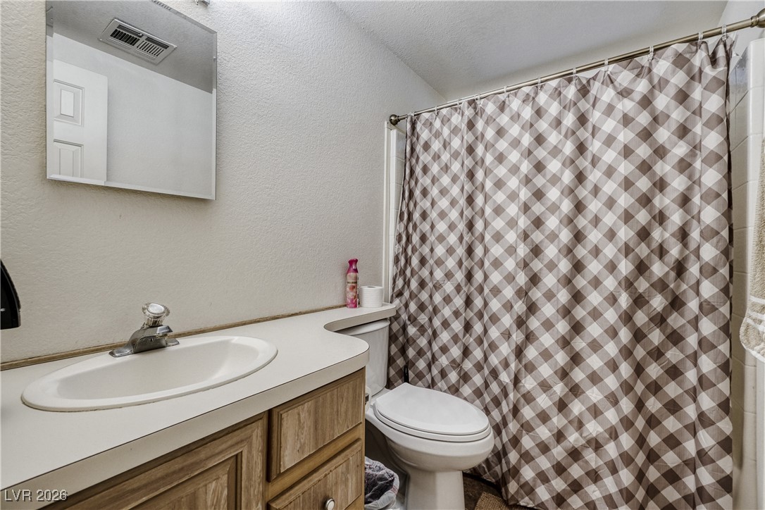 4552 Royal Ridge Avenue Las Vegas, NV 89103 - Photo 10 of 13 Bathroom with a textured wall, vanity, a shower with shower curtain, and a textured ceiling