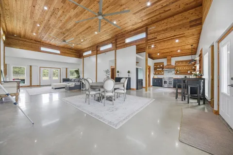a view of a dining room with furniture a chandelier and kitchen view