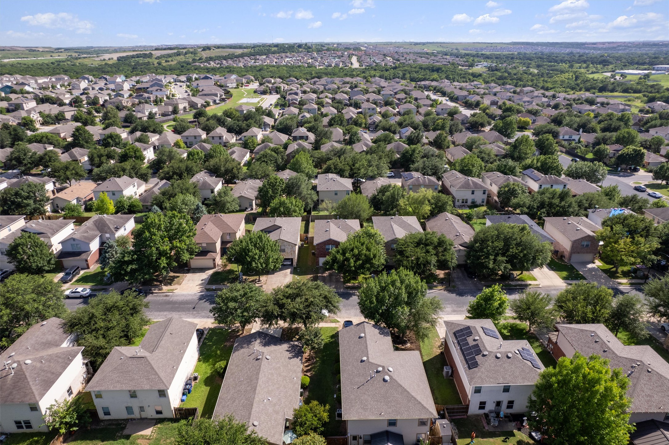 5825 Silver Screen Drive Austin, TX 78747 - Photo 2 of 40 An aerial perspective reveals a tree-lined neighborhood with uniform houses and verdant surroundings.
