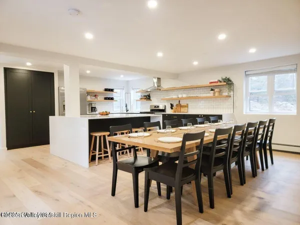 a dining area with stainless steel appliances kitchen island granite countertop a dining table chairs and a refrigerator