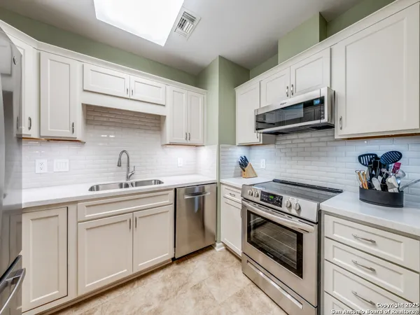 a kitchen with cabinets stainless steel appliances and sink