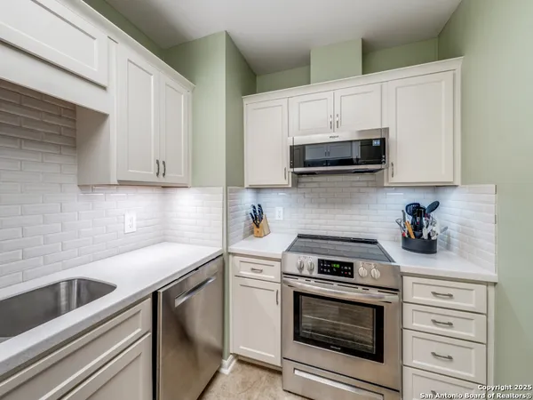 a kitchen with white cabinets and stainless steel appliances