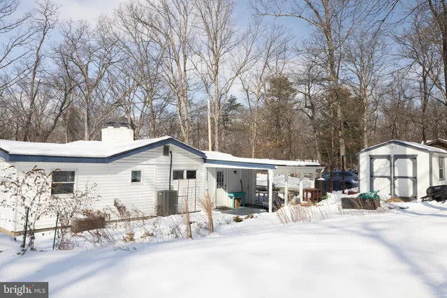 a view of a white house with a large tree and wooden fence