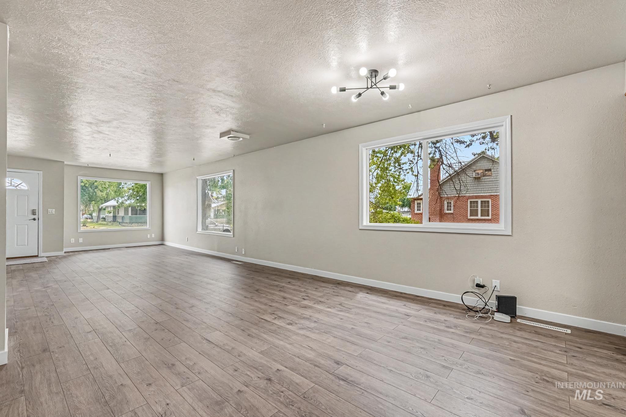1023 State Street Weiser, ID 83672 - Photo 6 of 25 Spacious room featuring wood-finish flooring, light neutral wall paint, and multiple windows with white trim