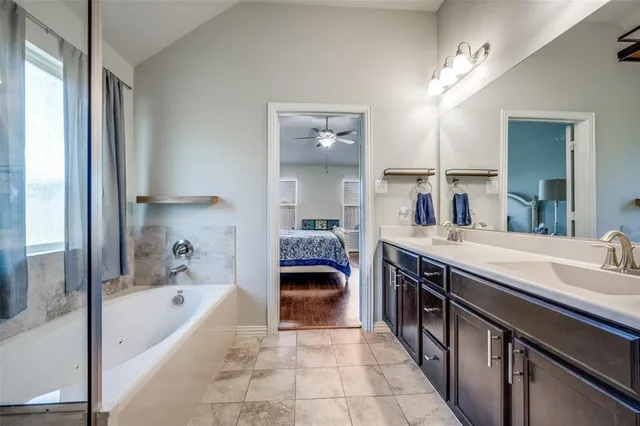 a bathroom with a tub double vanity sink and a large mirror