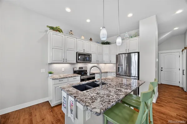 a kitchen with kitchen island stainless steel appliances a sink counter space and wooden floor