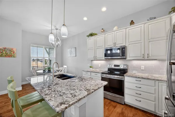 a kitchen with stainless steel appliances granite countertop a stove oven and a white cabinets