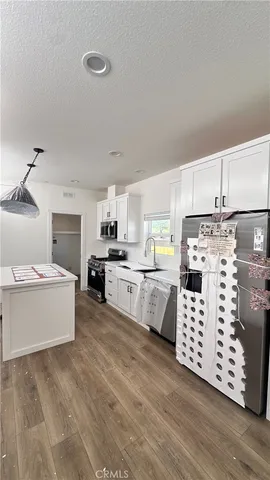 a kitchen with cabinets wooden floor and white appliances