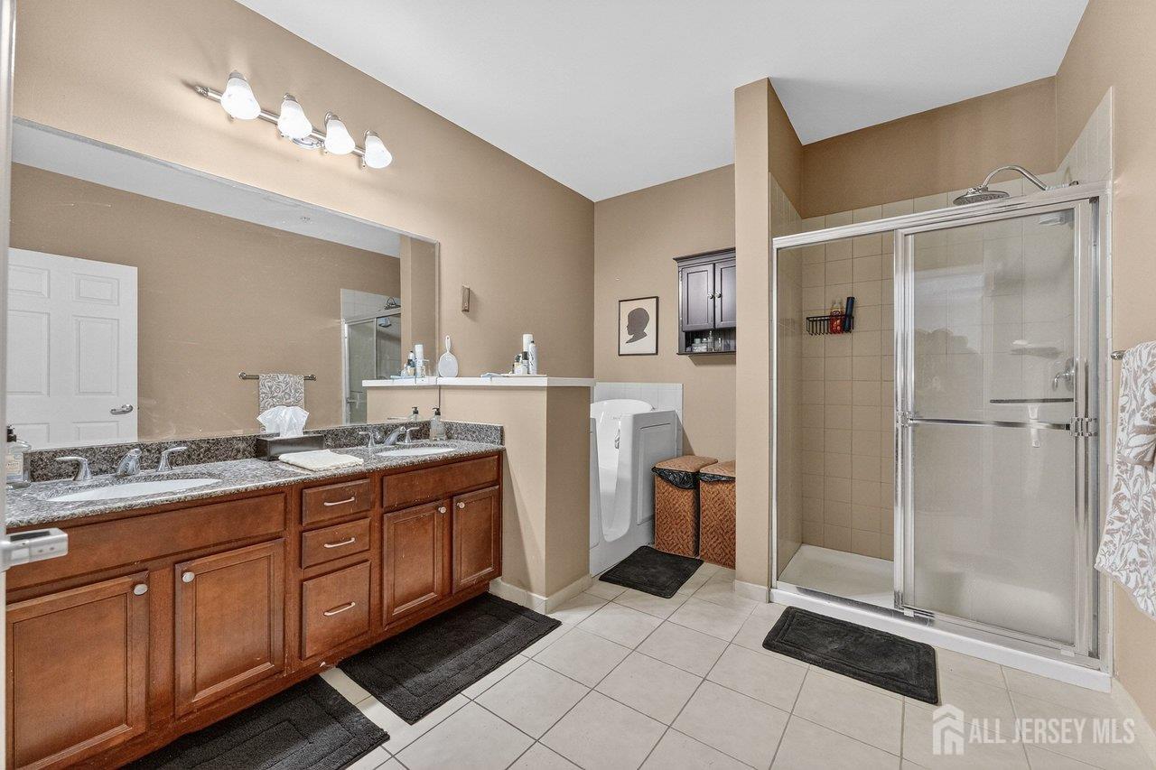 417 Regency Place Woodbridge, NJ 07095 - Photo 16 of 28 a spacious bathroom with a double vanity sink a large mirror and a shower