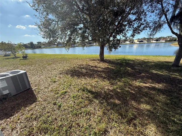 a view of a lake with a yard and large trees