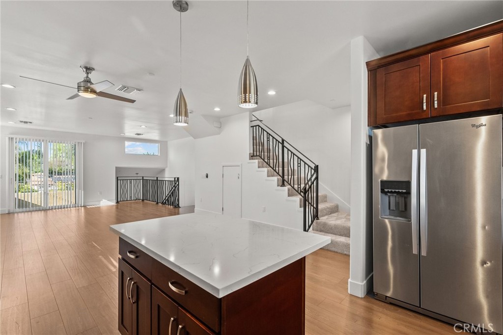 16863 Balboa Boulevard Van Nuys, CA 91406 - Photo 9 of 34 a kitchen with stainless steel appliances kitchen island granite countertop a refrigerator a stove and a sink with wooden floor