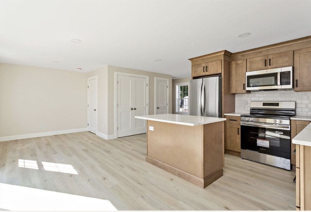 209 Main Street, Unit 4 Dennis, MA 02670 - Photo 14 of 26 a kitchen with stainless steel appliances wooden cabinets and stove top oven