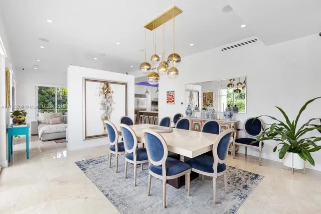 a view of a dining room and livingroom with furniture a rug a potted plant and a chandelier